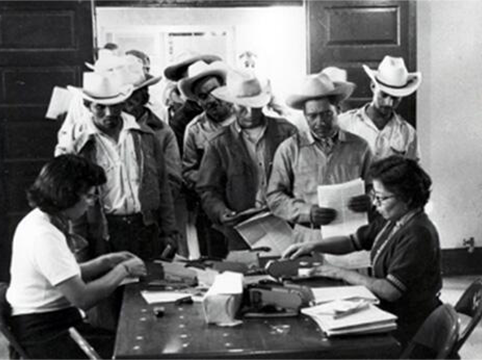 Image of Temporary clerks receiving typed forms I-100(a) and (b) (micas) were then presented to clerks who stapled photographs to the cards.  Rio Vista Reception Center, El Paso, Texas.