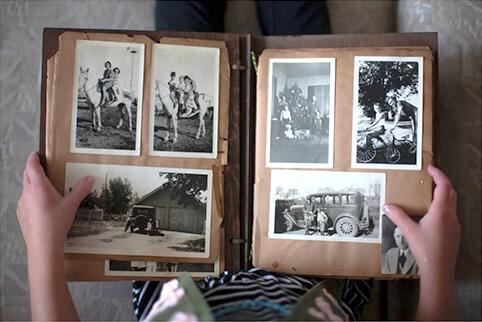 Photo album of old photos open on a person's lap.